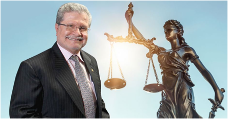 Descripcin: Un hombre mayor de bigote sonre junto a una estaua de la justicia